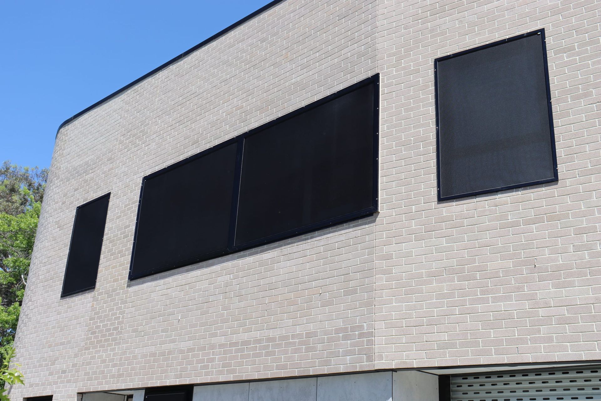 A white brick building with black windows and a blue sky in the background.
