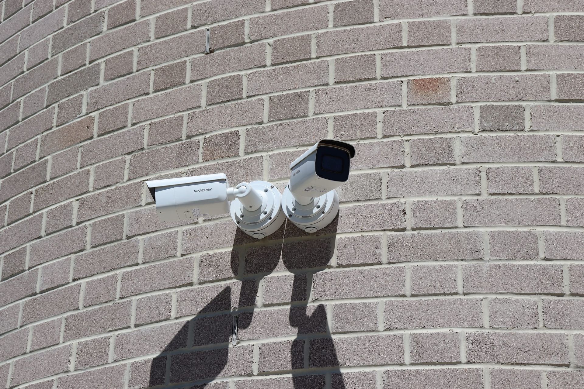 A security camera is mounted on the side of a brick building.