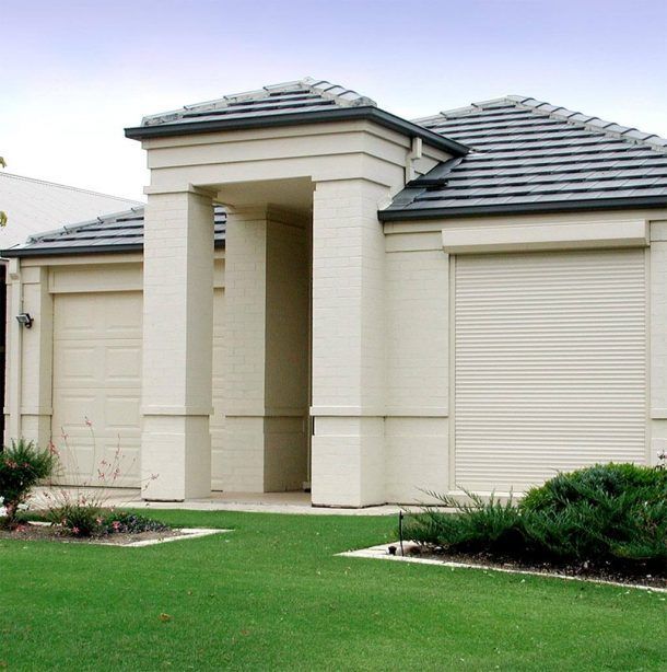 A white house with a black roof and a lush green lawn