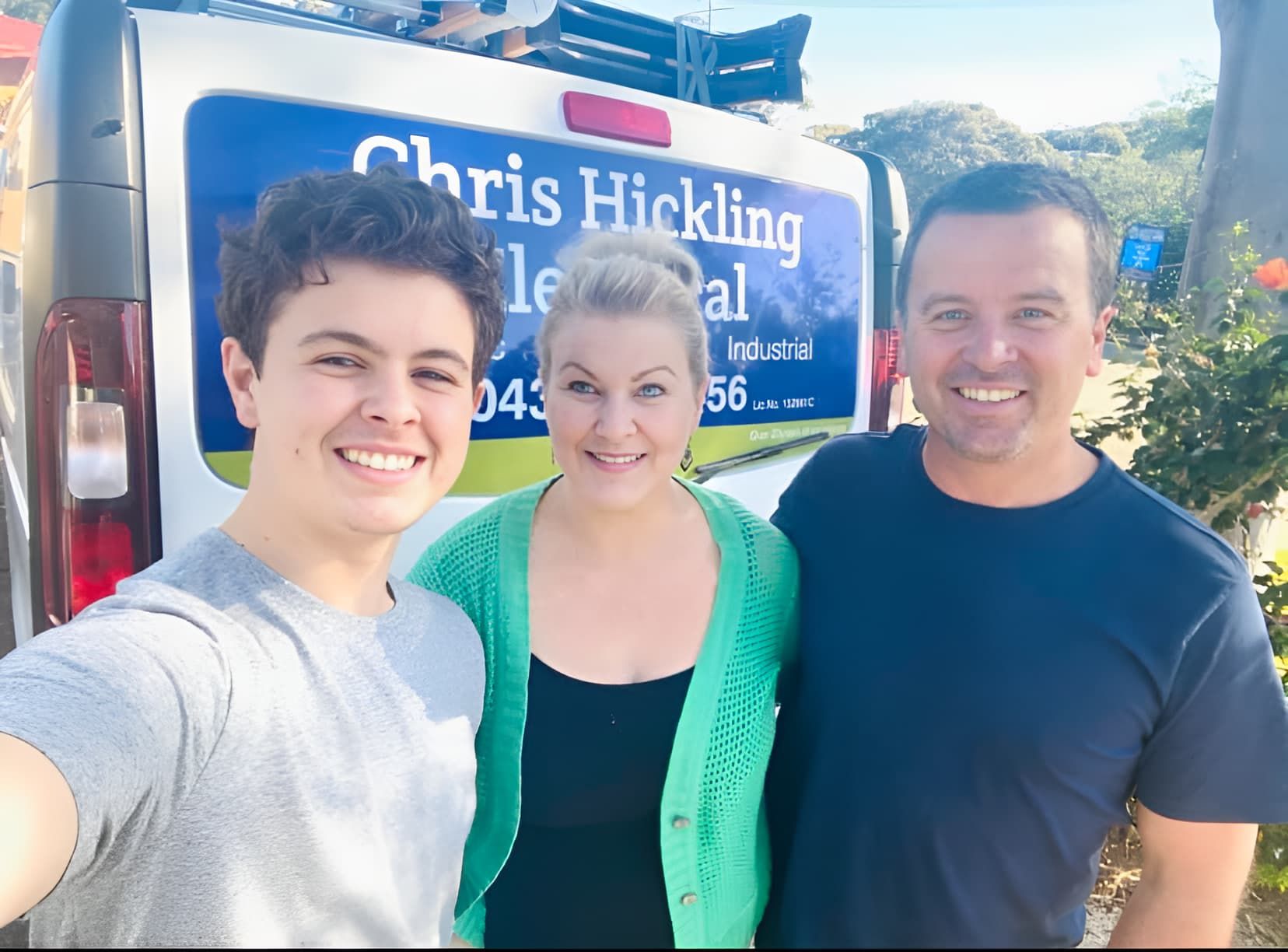 A man and two women are posing for a picture in front of a van that says chris hickling — Chris Hickling Electrical In Port Macquarie, NSW