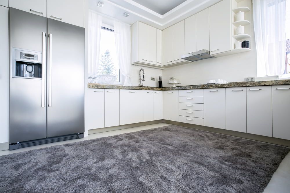 A Kitchen With White Cabinets And A Stainless Steel Refrigerator  — Floorgard in Wamberal, NSW