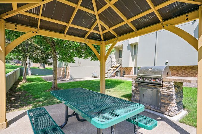 Photo showing a barbecue grill and a canopy with a bench underneath it