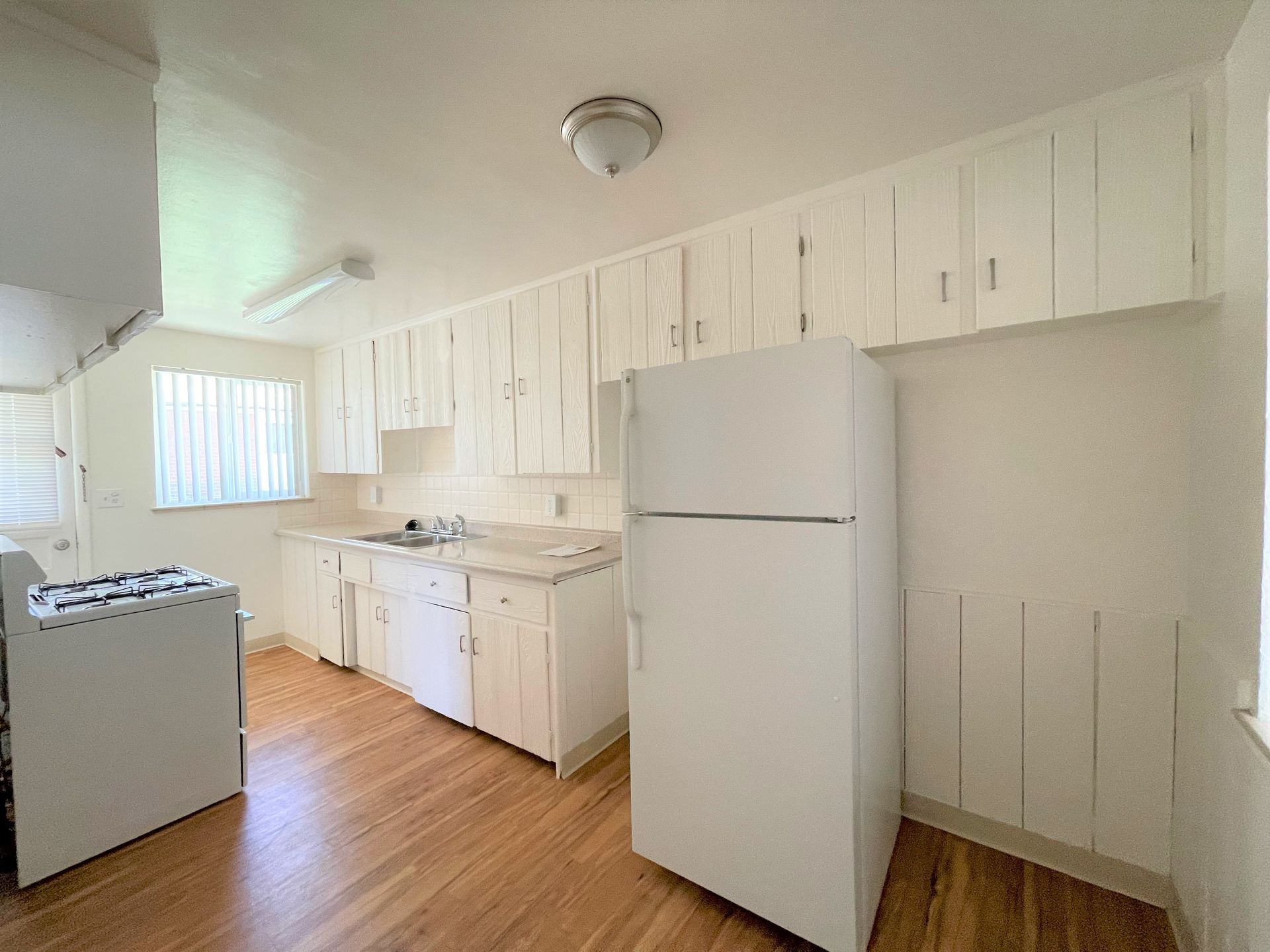 A kitchen with plenty of natural light, as it has an exterior-facing door with a window, in addition to the window already in the kitchen
