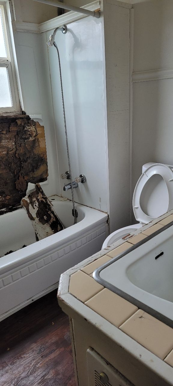 Dilapidated bathroom with a bathtub, toilet, and sink.