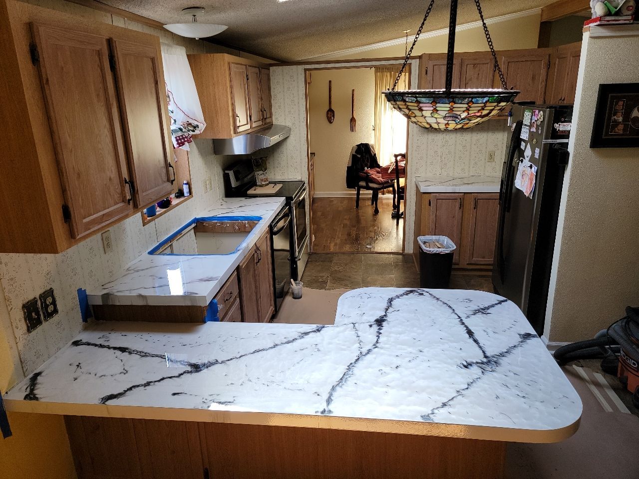 Kitchen with white countertops, brown cabinets, and an open doorway to another room.