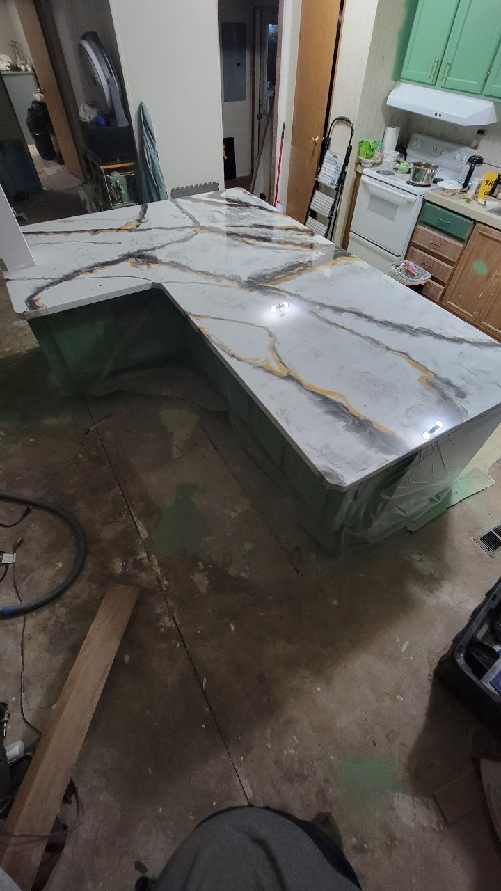 L-shaped kitchen countertop, white with gold veining, sitting in a room under construction.