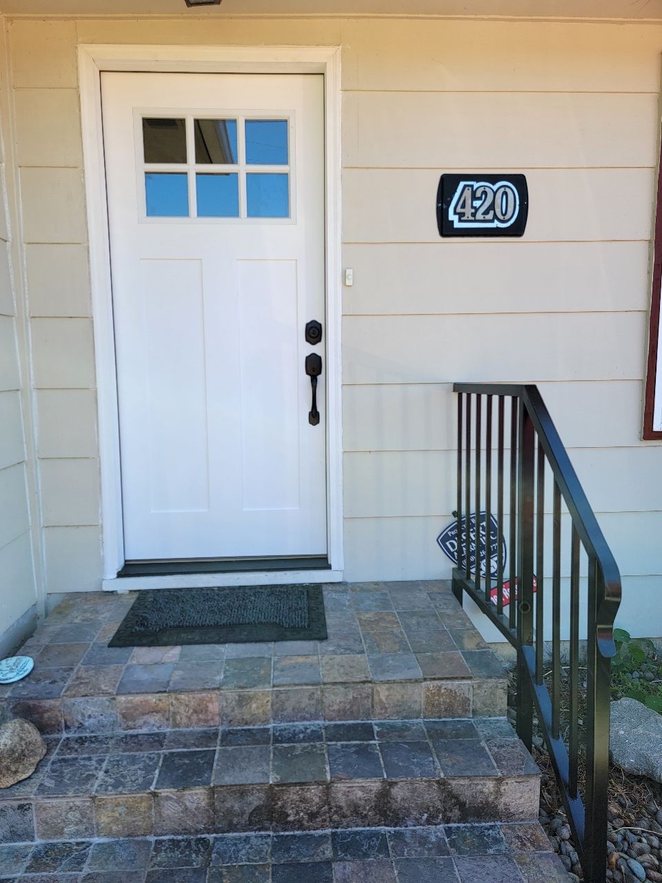 White door with glass panes, house number 420, steps with railing, and a doormat.