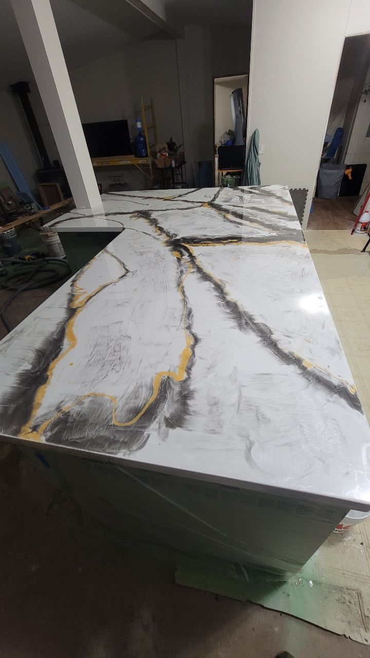White countertop with black and gold veining, on a green island.
