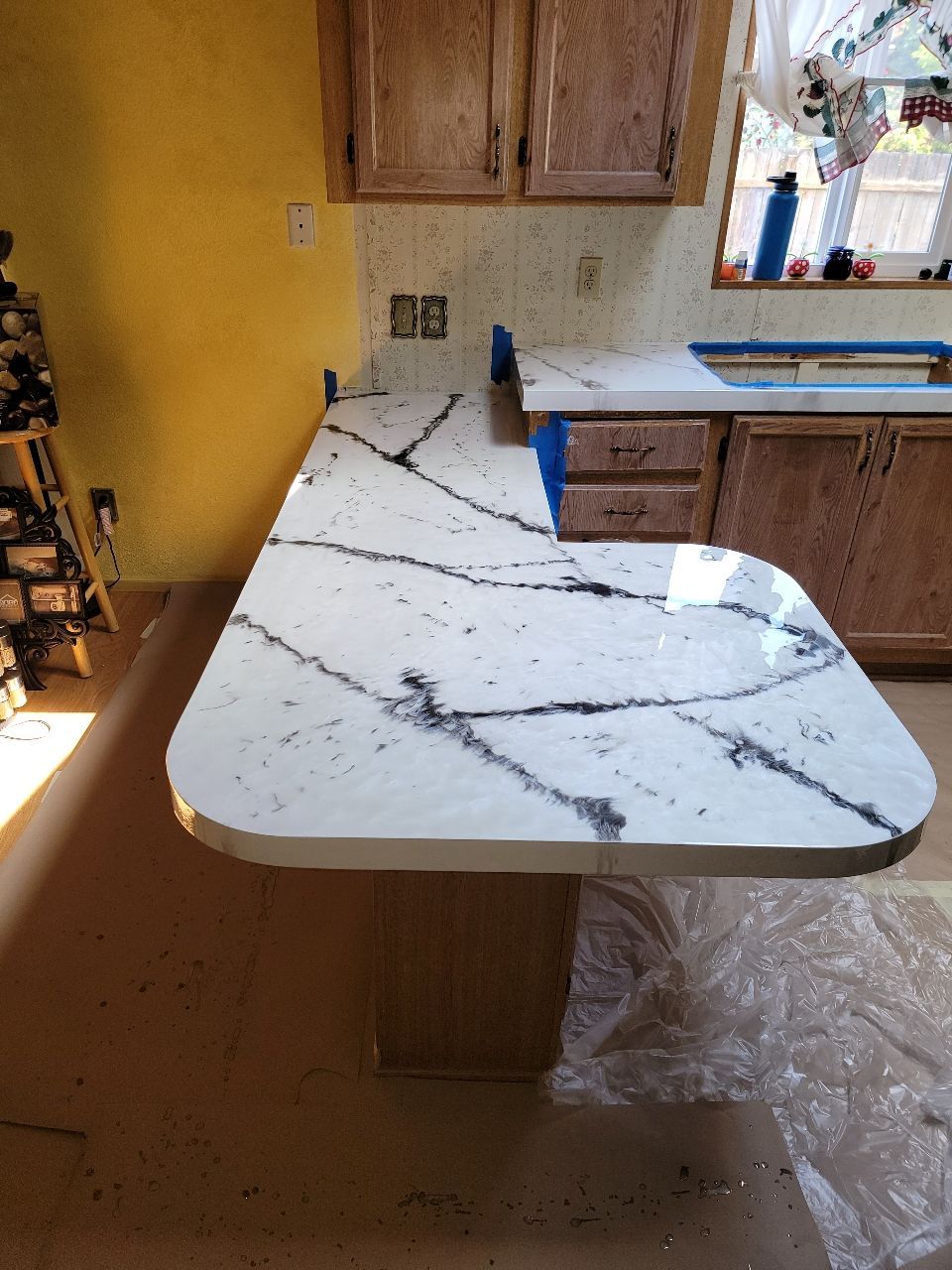 Kitchen countertop with white and gray veining, installed. Wooden cabinets and yellow wall are visible.