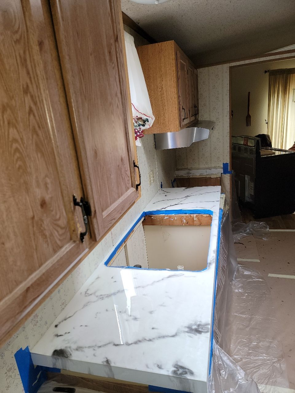 Kitchen with white marble countertop, wooden cabinets, and stainless steel vent hood.