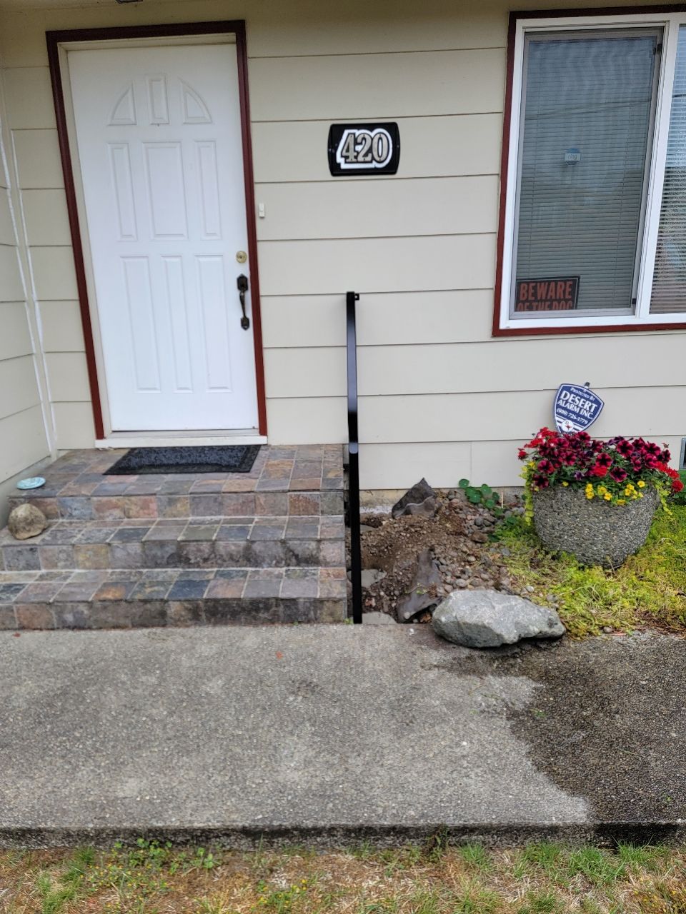 Front entrance with steps, a door, and a security camera. Black handrail and address 420.