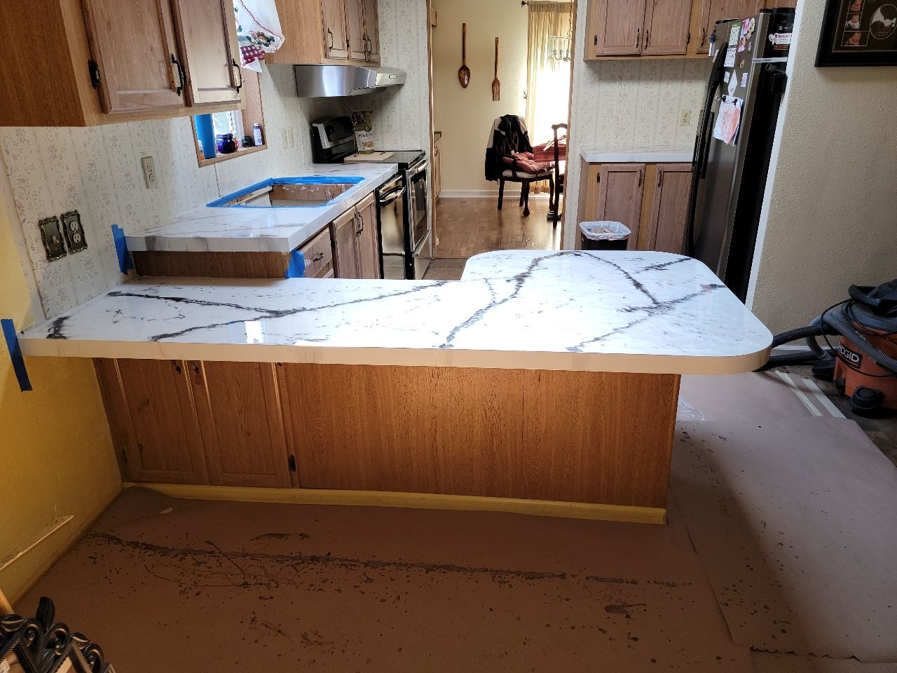 Kitchen renovation: Installing white quartz countertops with gray veining, over oak cabinets.