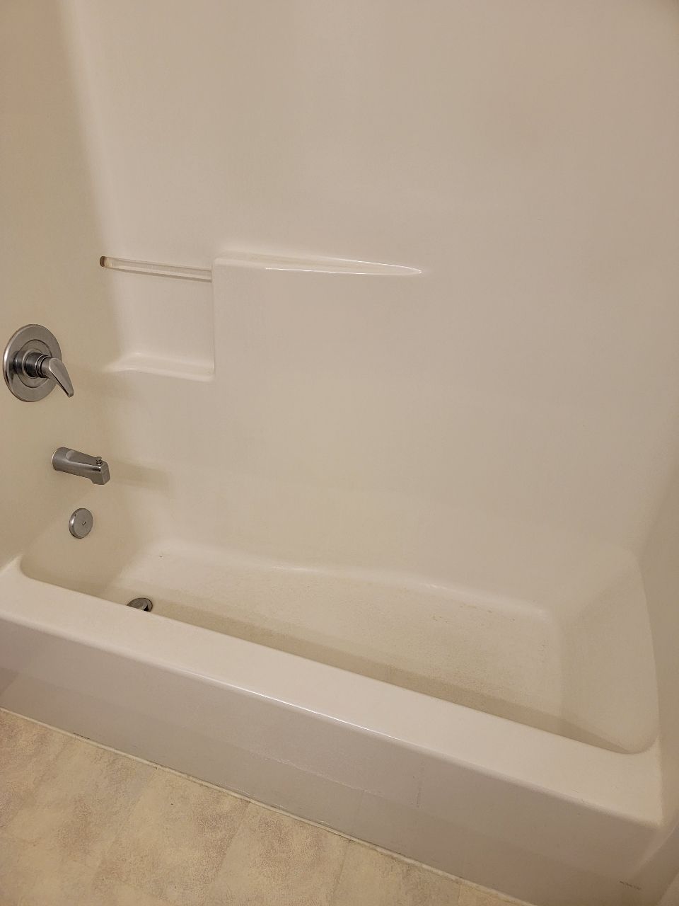 White bathtub and surround with fixtures.