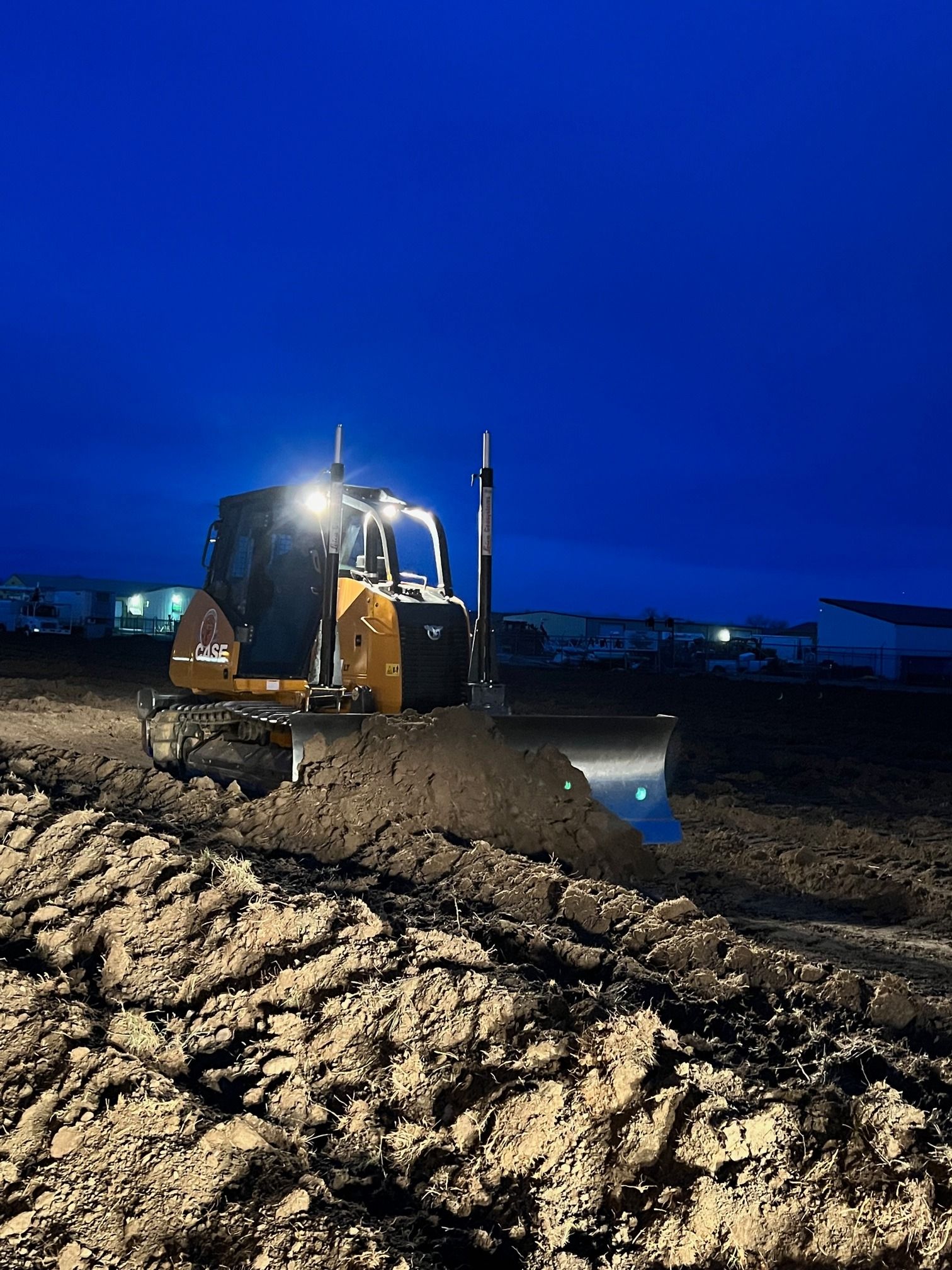 A bulldozer is working on a dirt field at night.