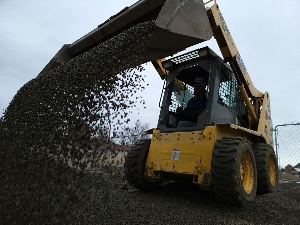A yellow bulldozer is loading gravel into a pile