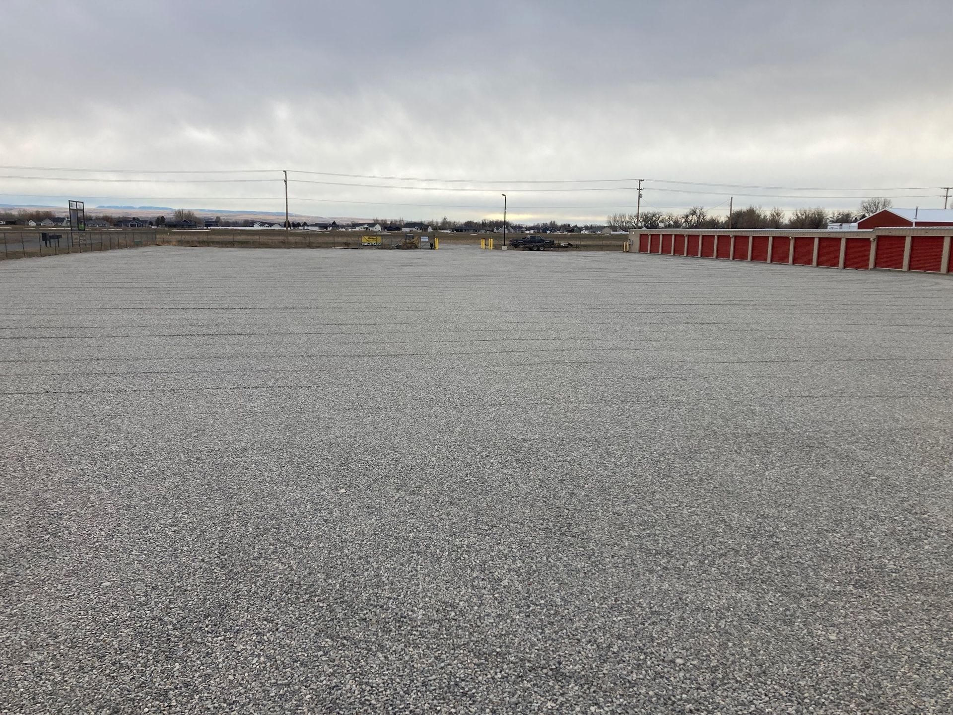 A large gravel area with a red building in the background