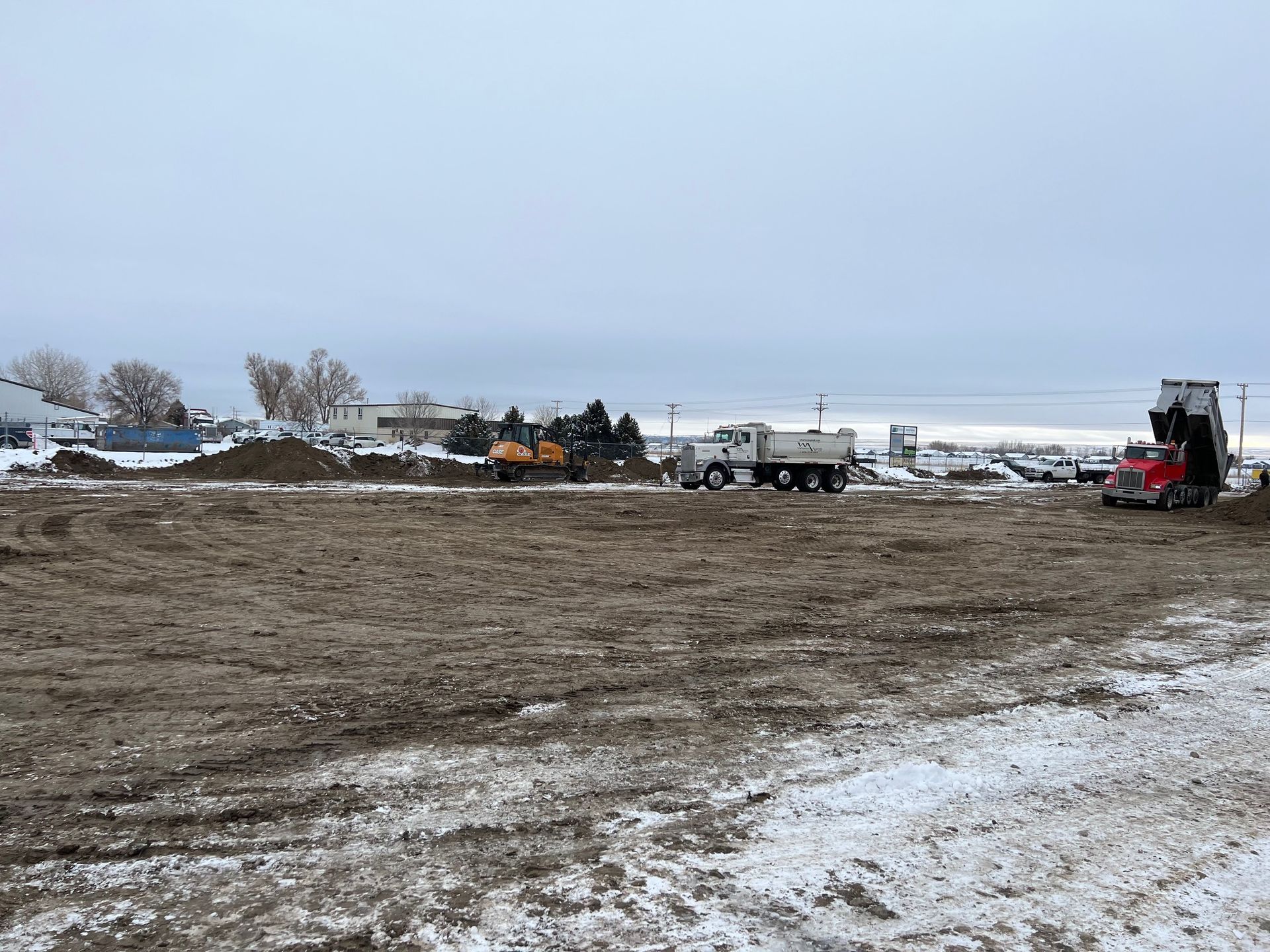 A dump truck is sitting in the middle of a snowy field.