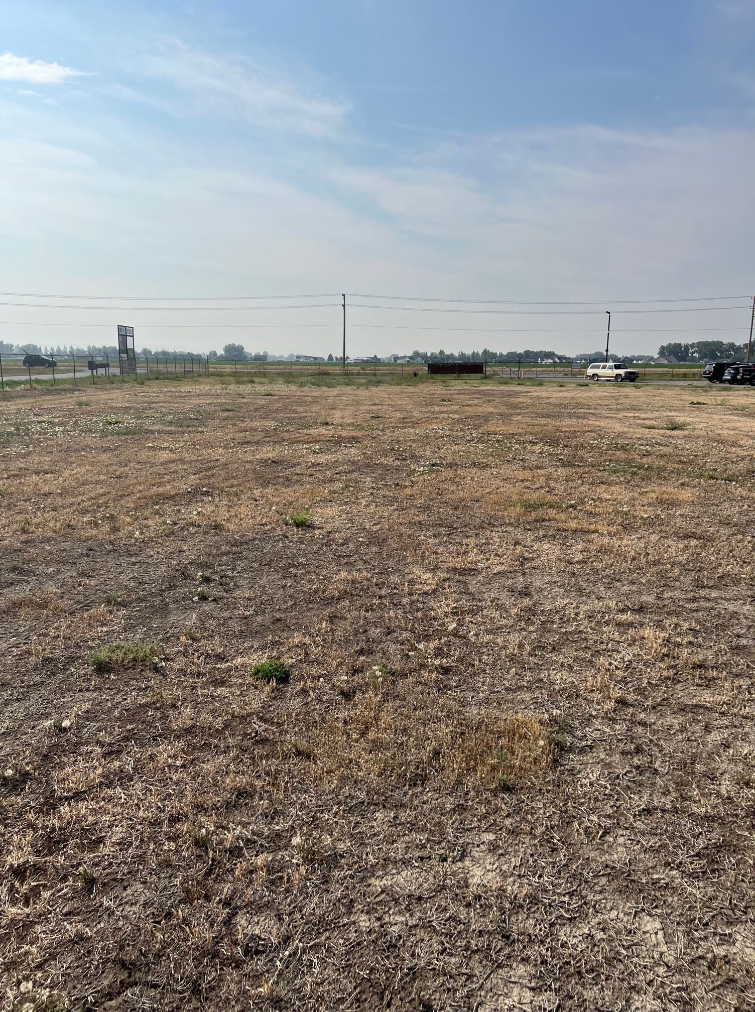 A large dry field with a fence in the background.