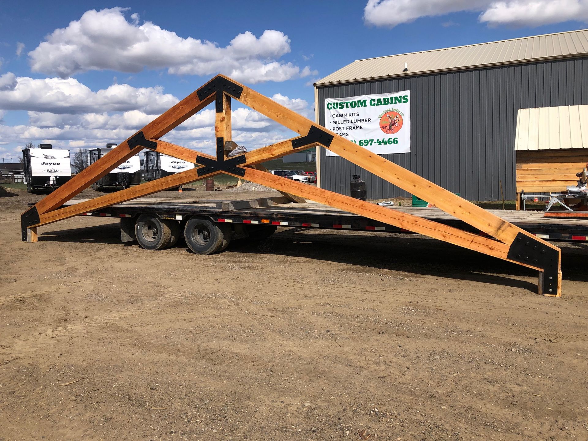 A large wooden structure is on a trailer in front of a building with a sign that says country crafts
