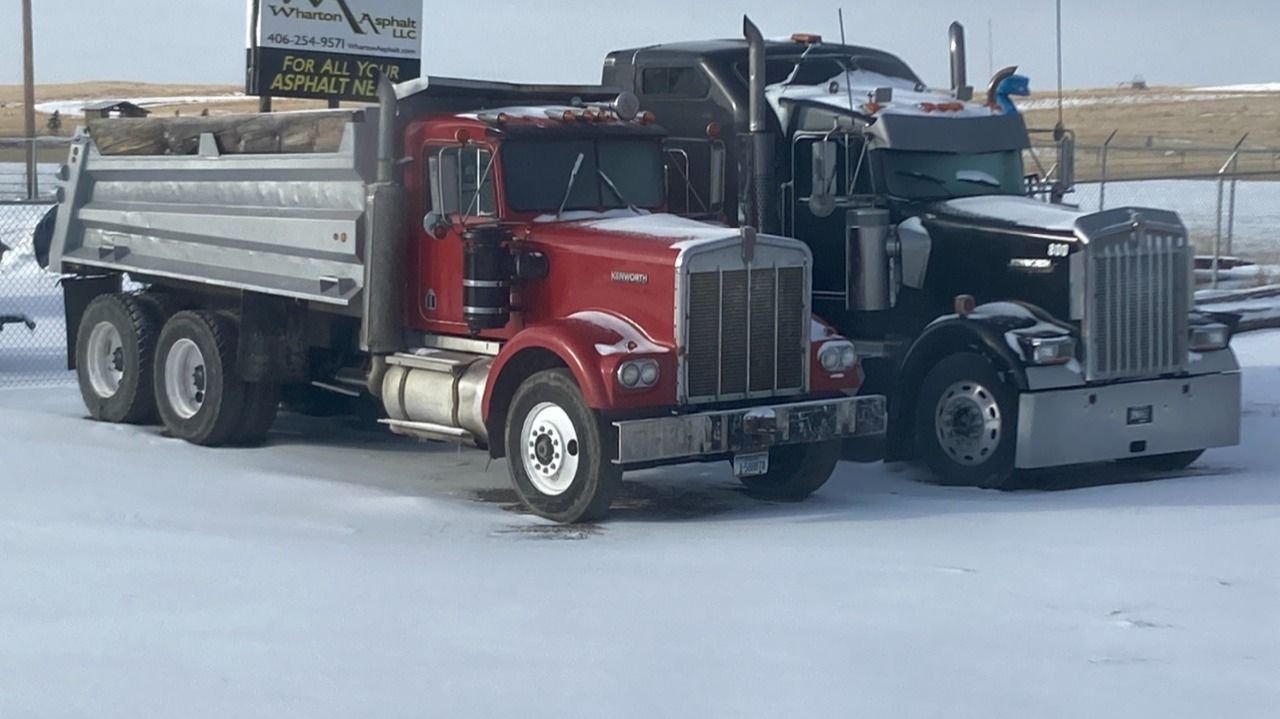 Two semi trucks are parked next to each other in the snow.