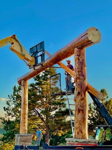 A man on a ladder is working on a large wooden structure
