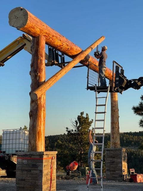 A man on a ladder is working on a wooden structure