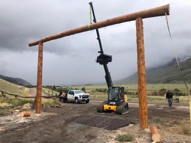 A crane is lifting a wooden pole in a field.