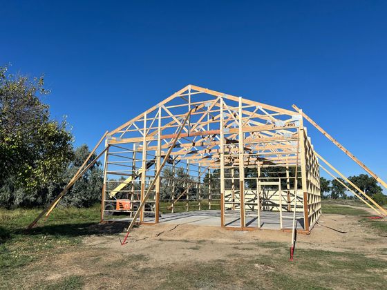 A large wooden structure is being built in a field.