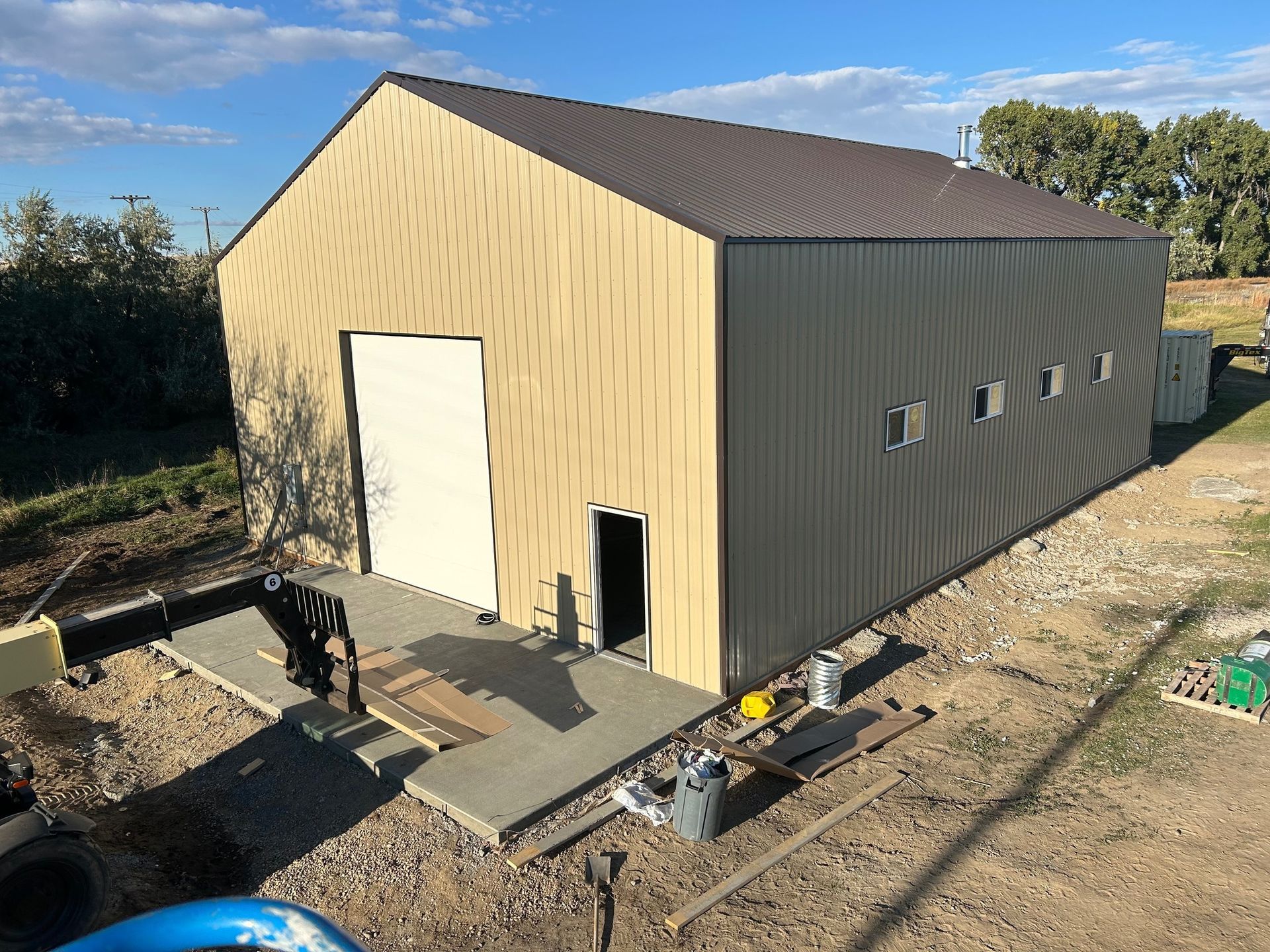A large metal building is being built on a dirt field.