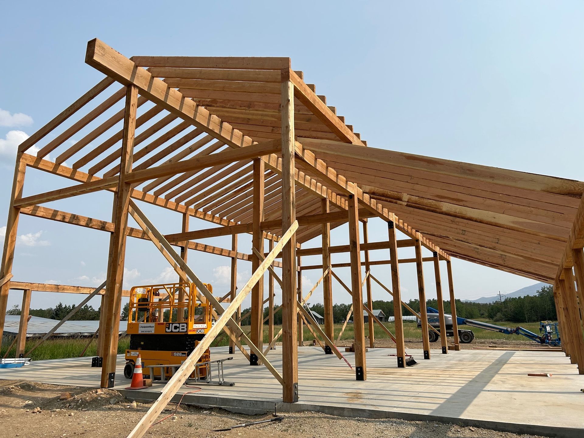 A large wooden structure is being built in a field.