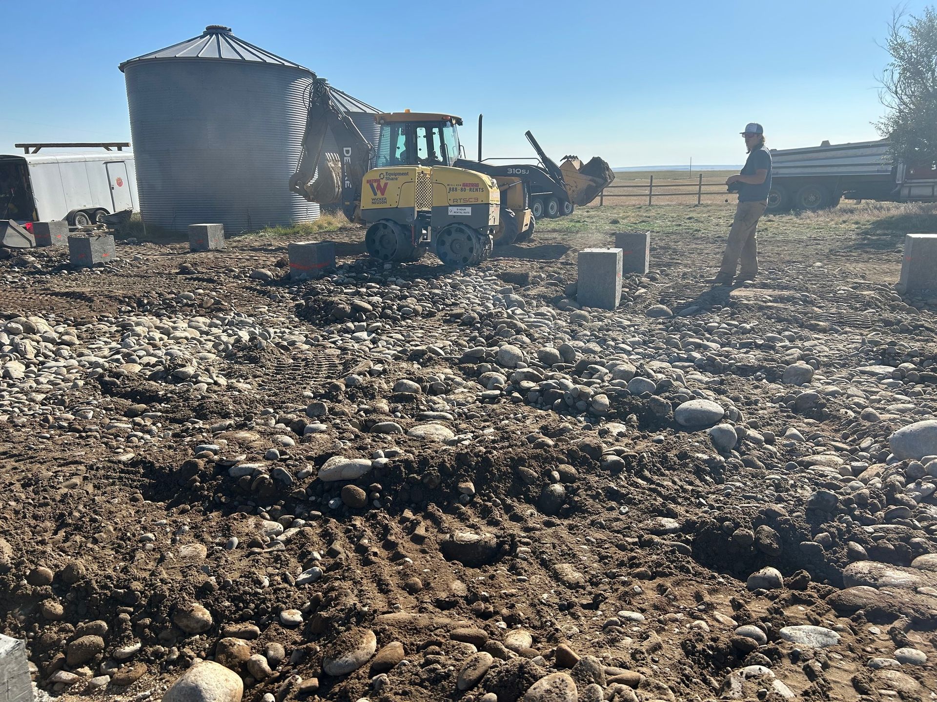 A man is standing in a field with a tractor in the background.