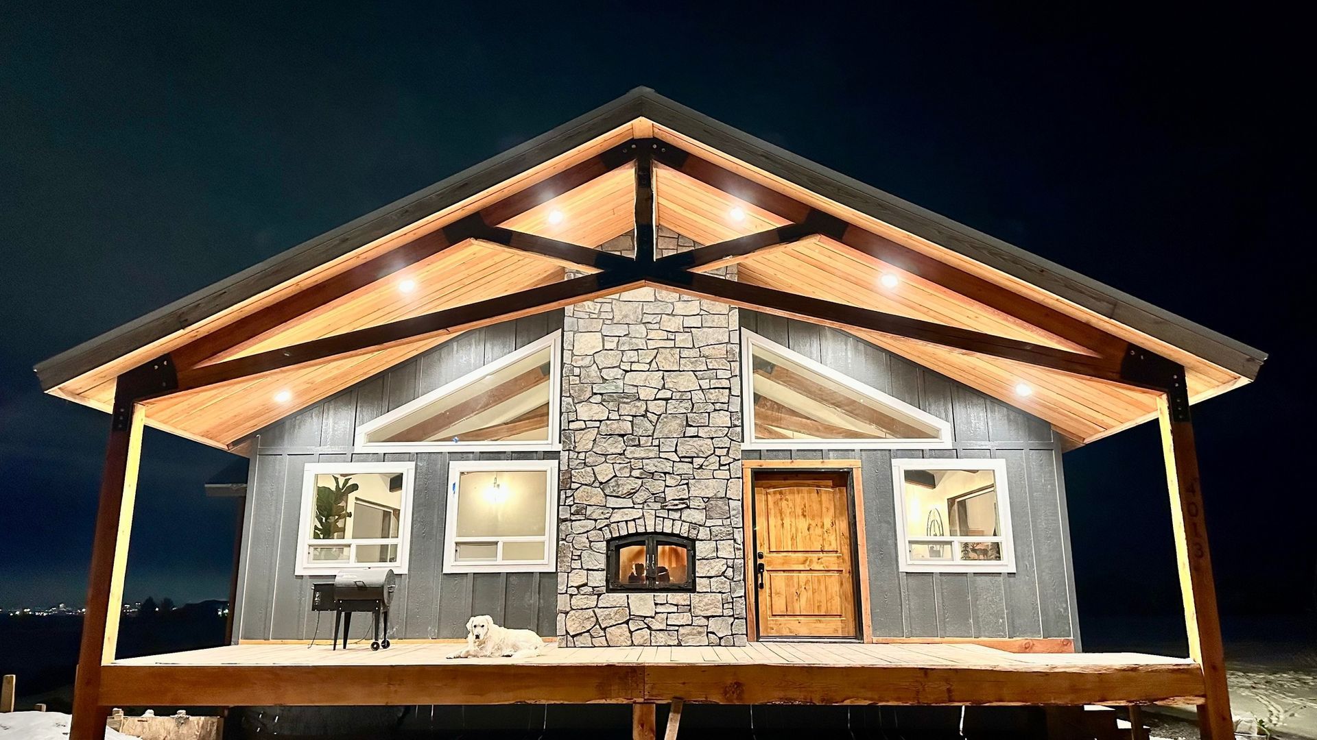 A house with a porch and a fireplace is lit up at night.