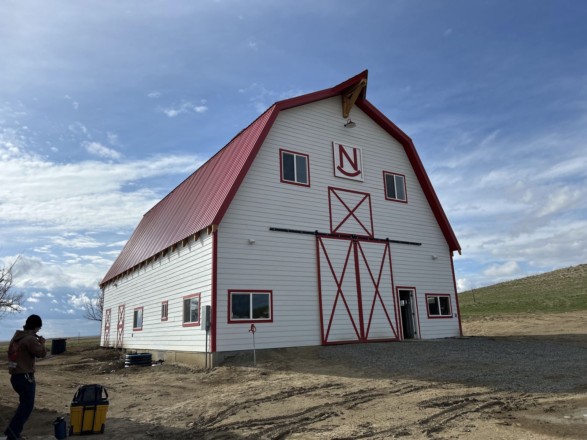 A large metal building is being built in a dirt field.