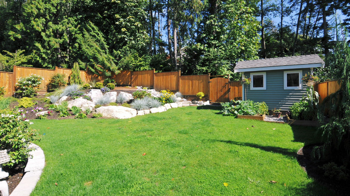 Tree trimming crew using a lift bucket to cut branches near power lines, with a red truck and chipper on a driveway.