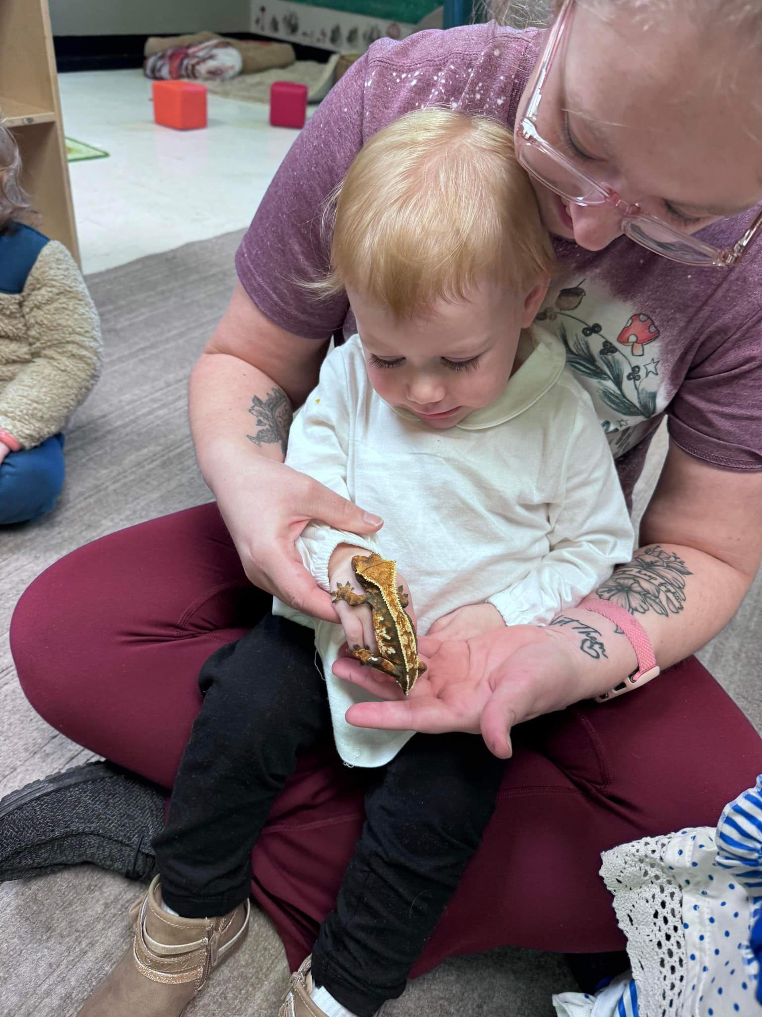 A woman is sitting on the floor holding a baby.