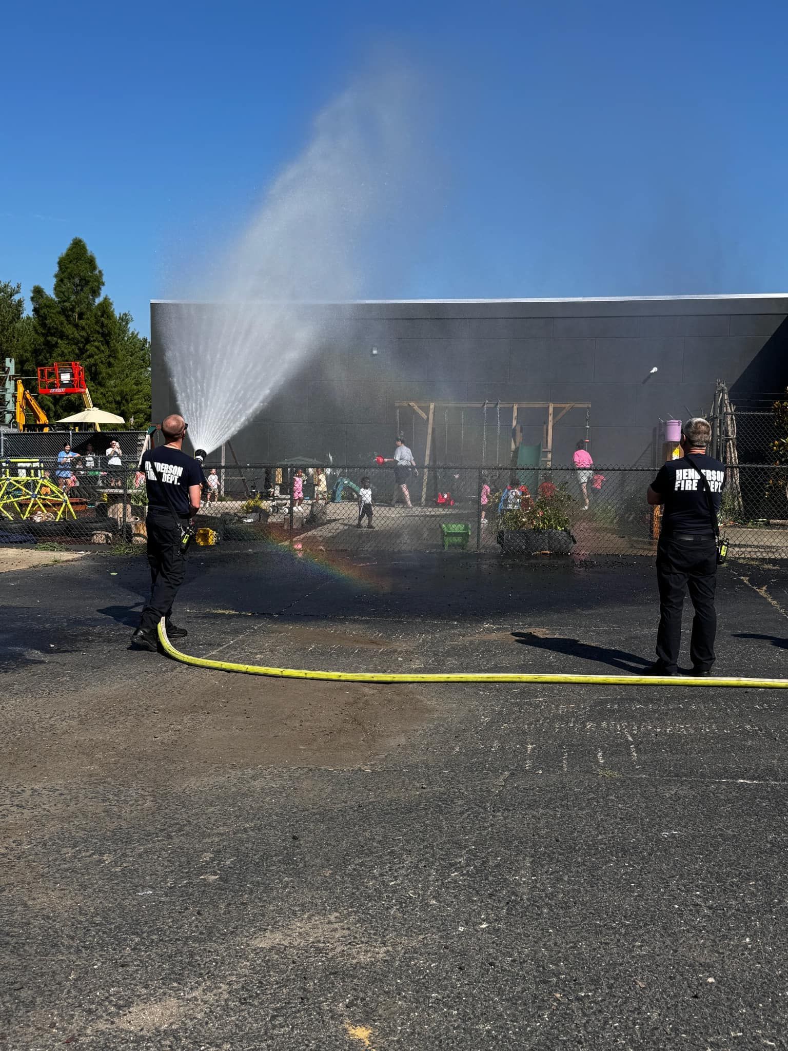 Two firefighters are spraying water on a fire in a parking lot.