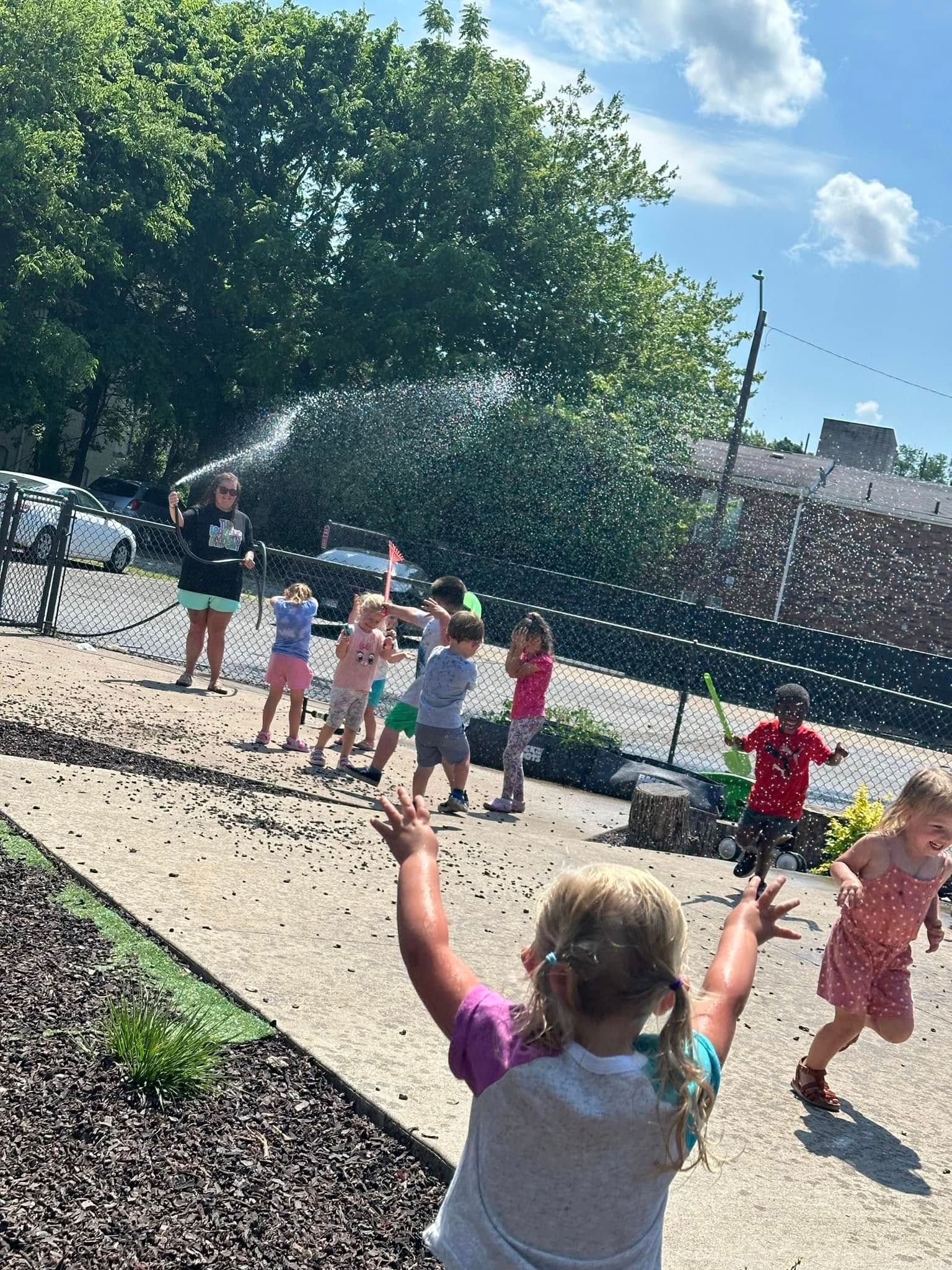 A group of children are playing in the dirt with a hose.