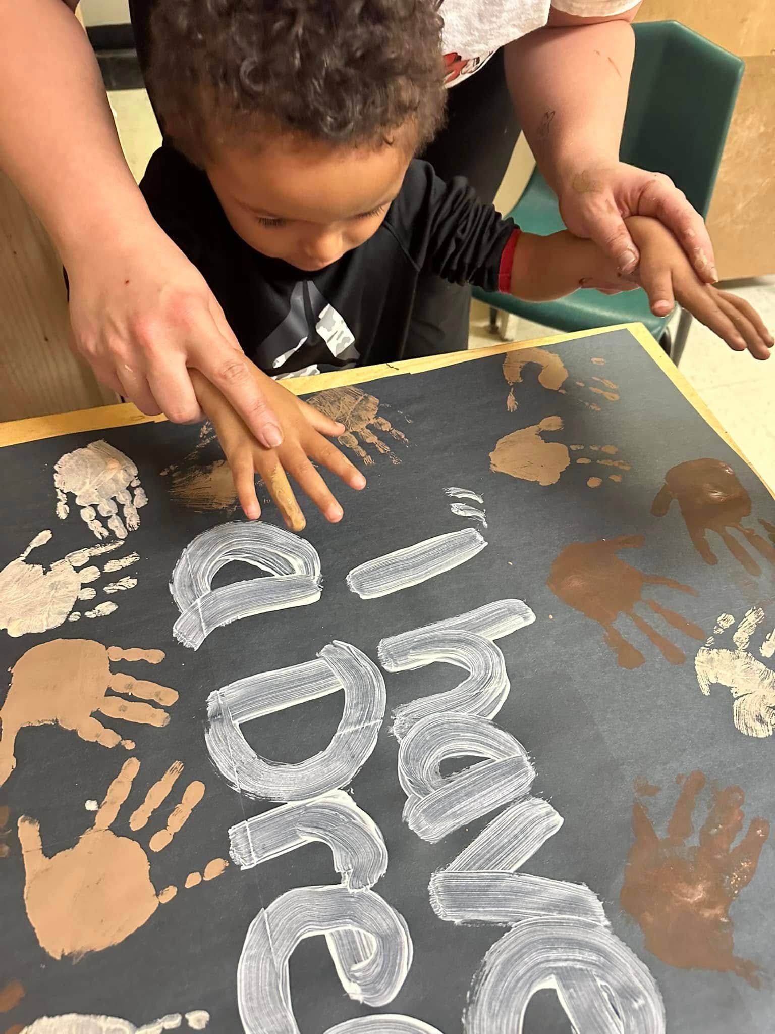 A young boy is playing with chalk on a chalkboard.