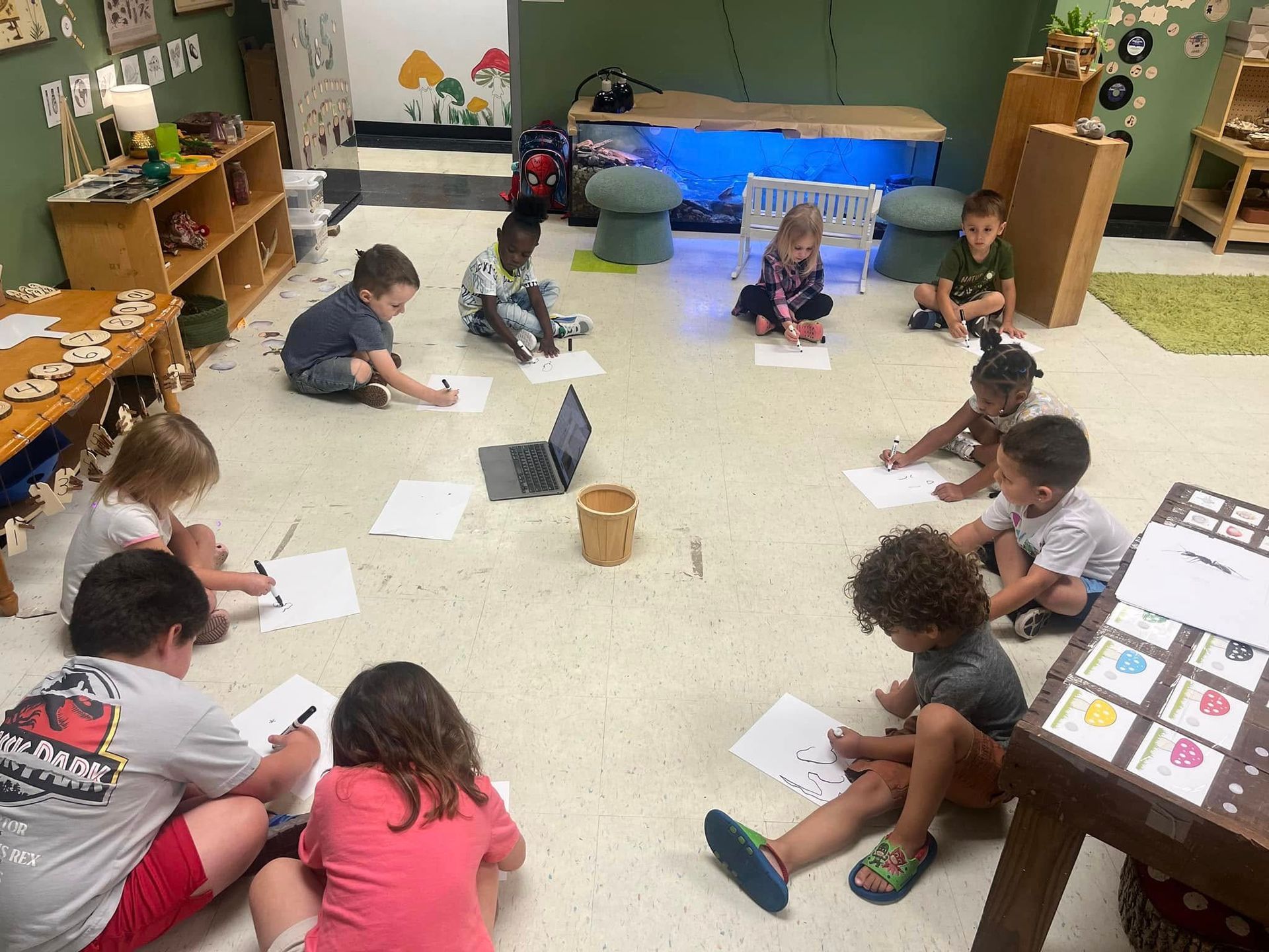 A group of children are sitting on the floor in a classroom.