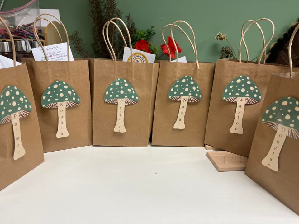 A row of brown paper bags with mushrooms on them are sitting on a table.