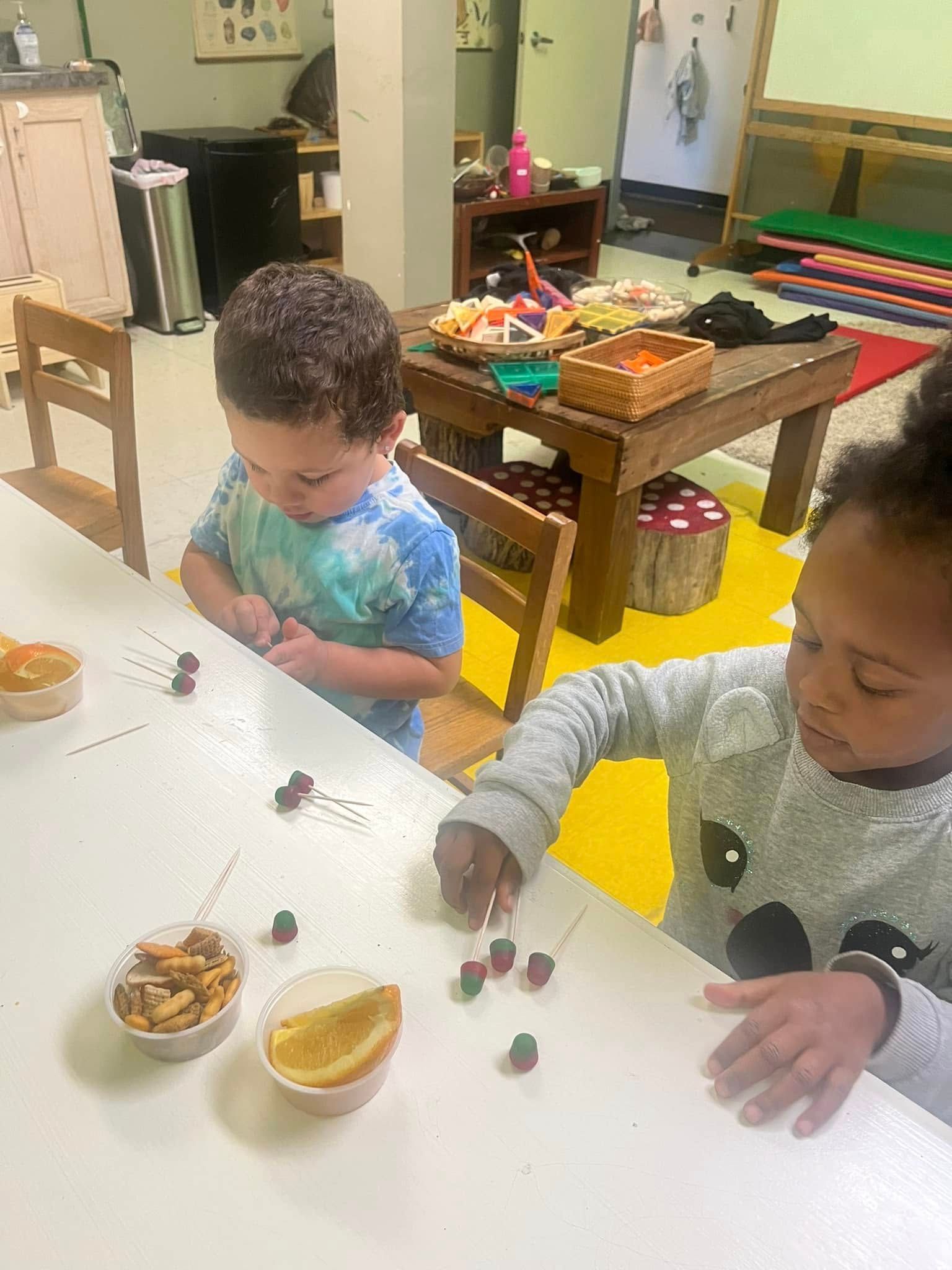 A boy and a girl are sitting at a table playing with food.