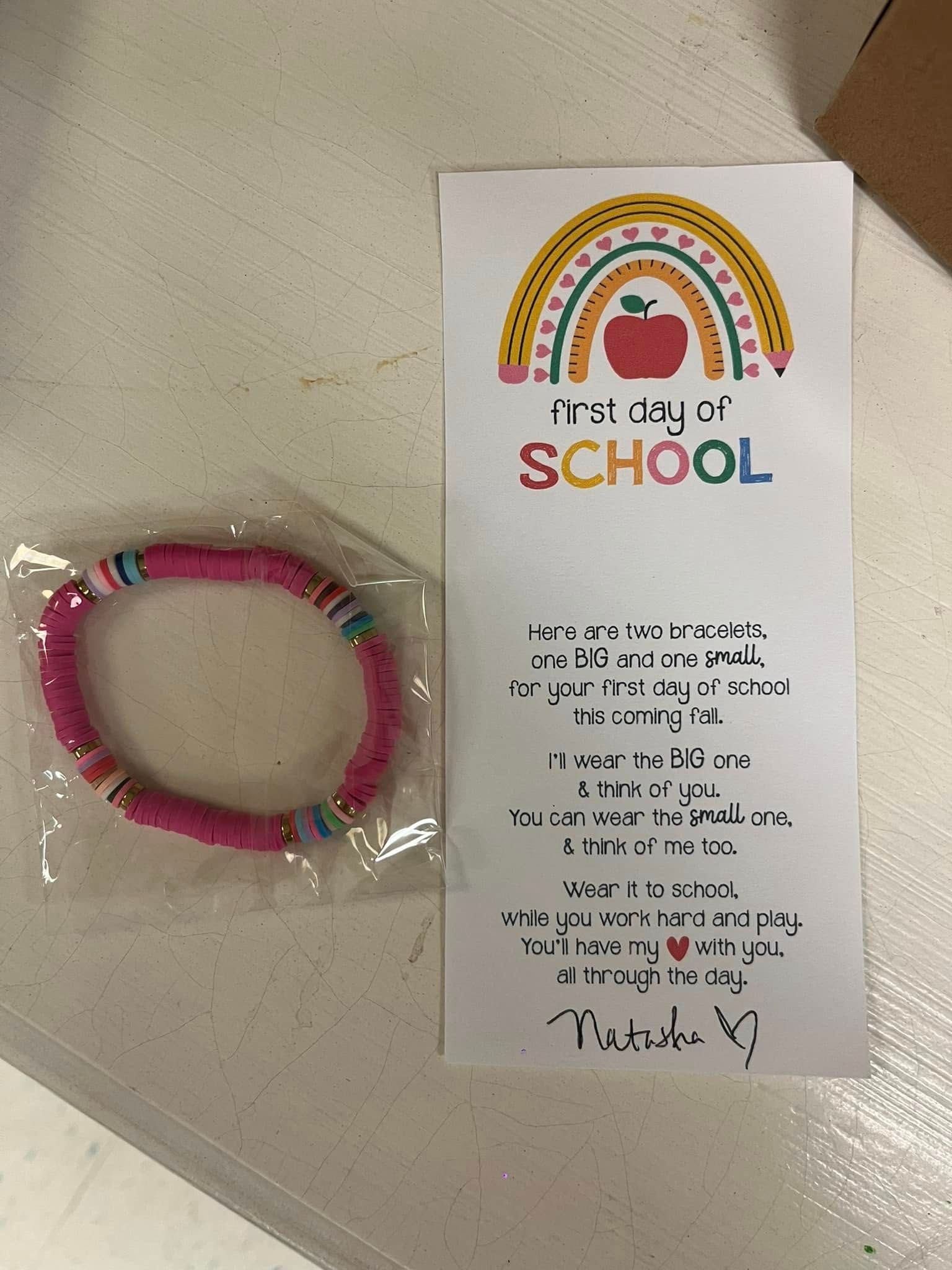 A pink bracelet is sitting next to a card that says i 'm ready for school