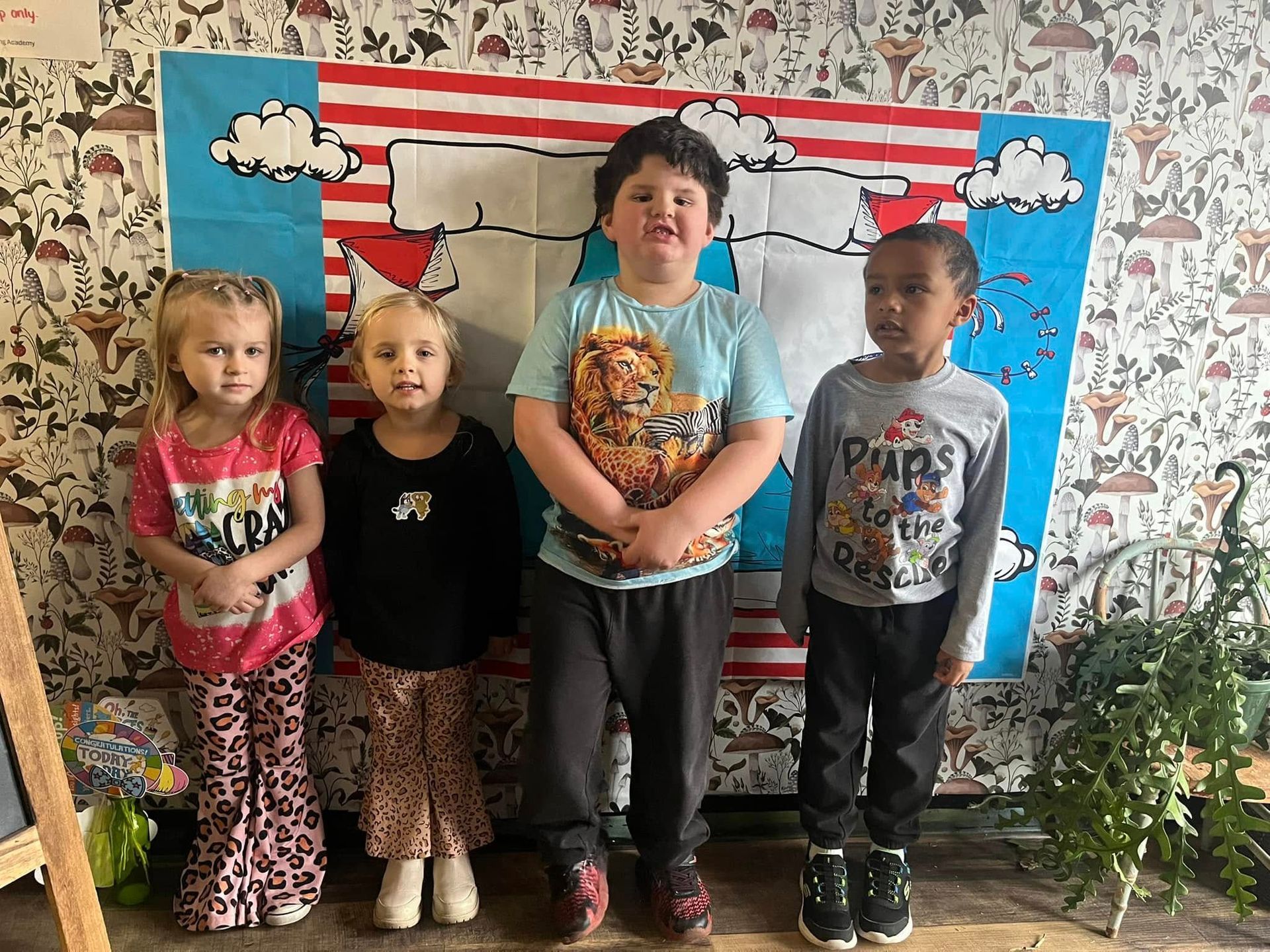 A group of children are posing for a picture in front of a wall.