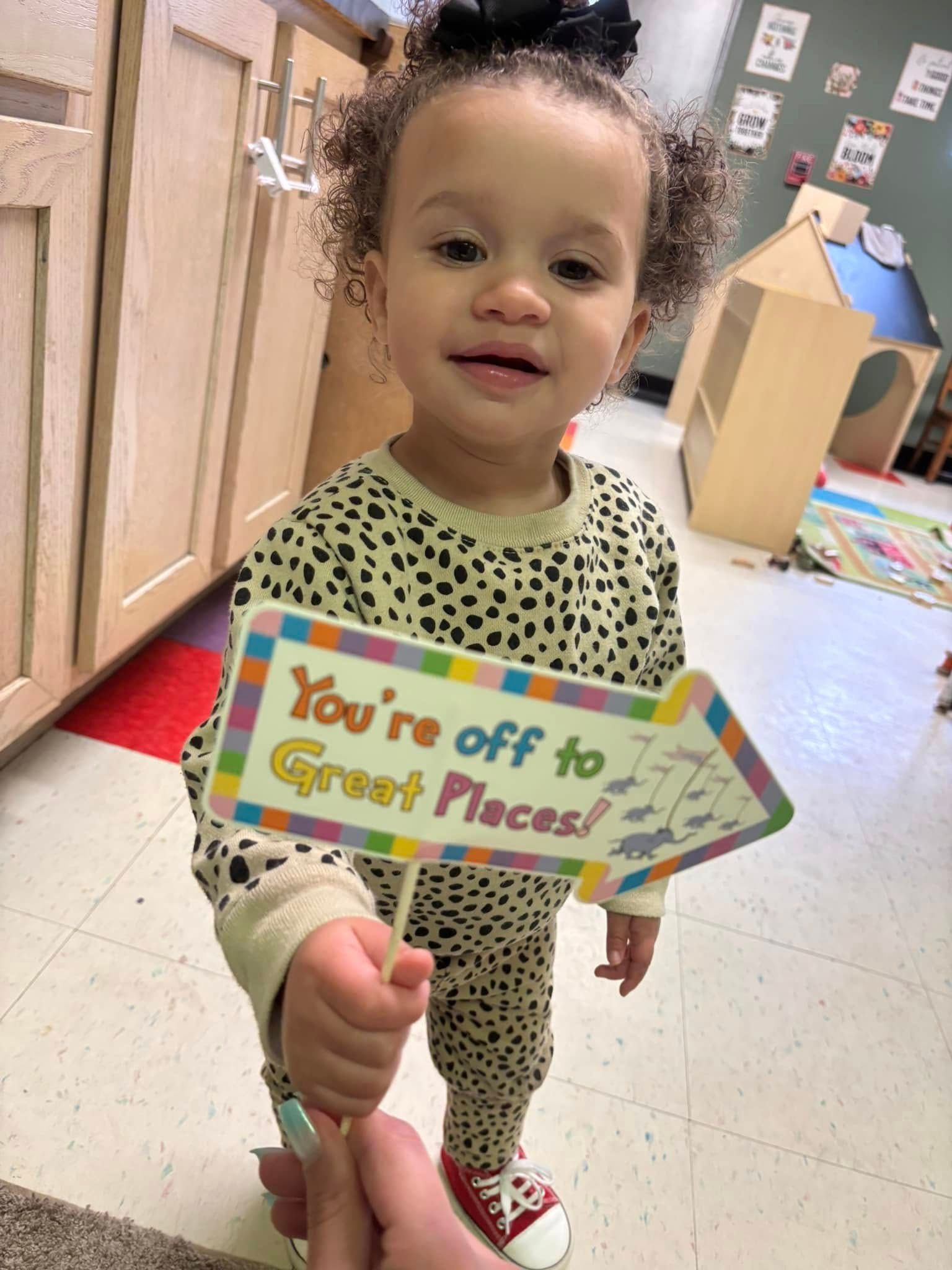A little girl is holding a sign that says `` you 're off to great places ''.