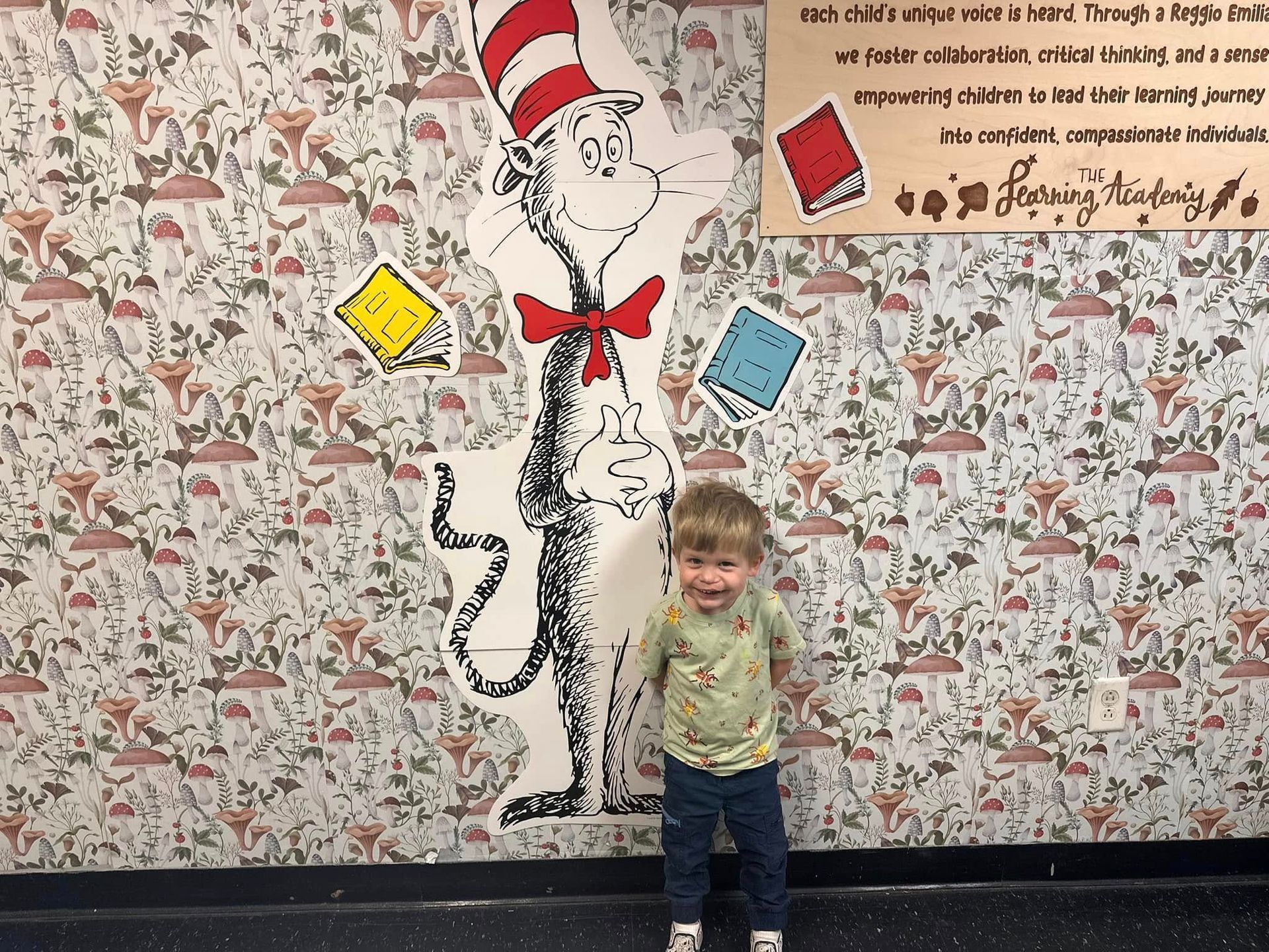 A little boy is standing in front of a cat in the hat mural.