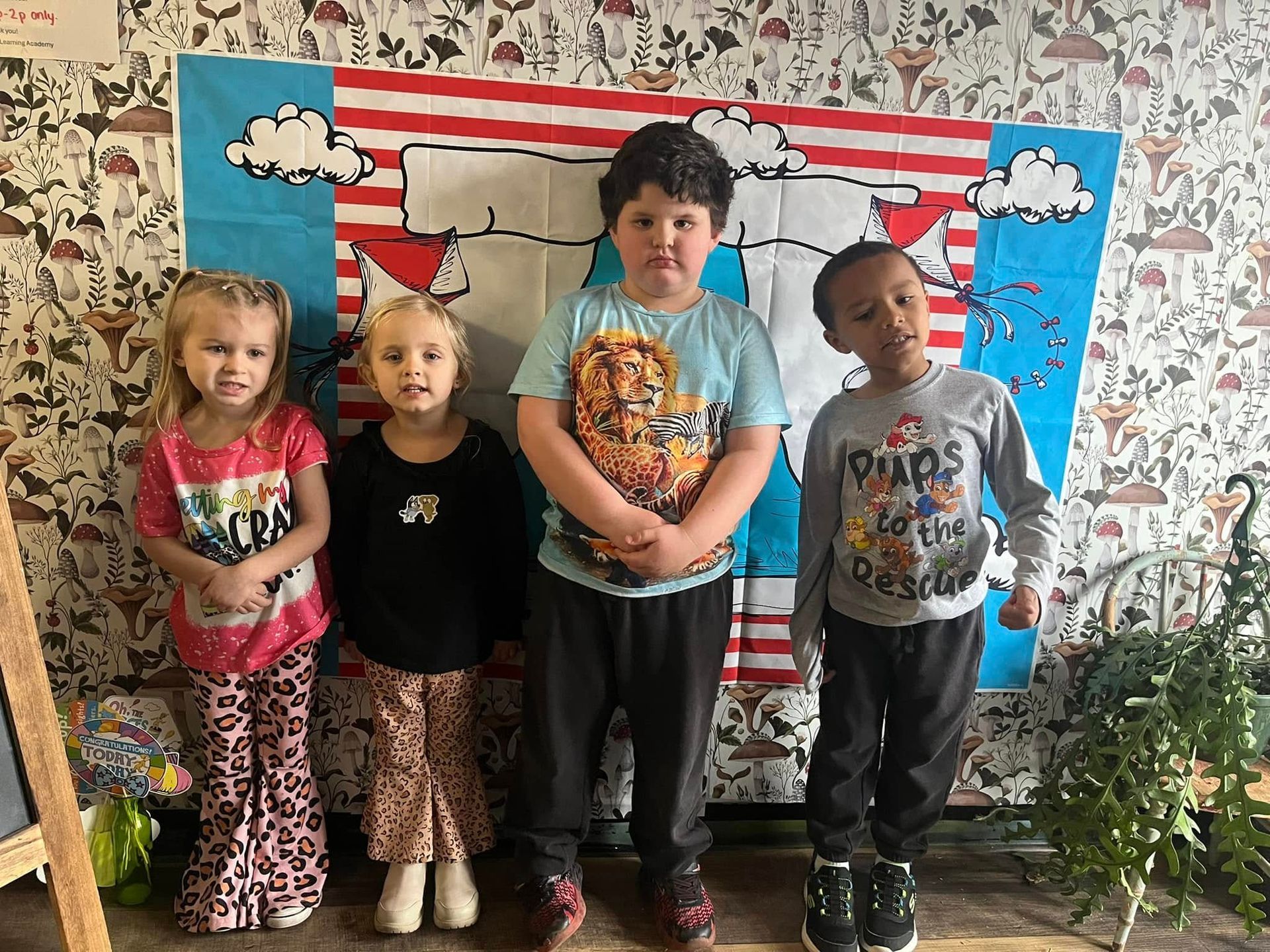 A group of children are standing next to each other in front of a wall.