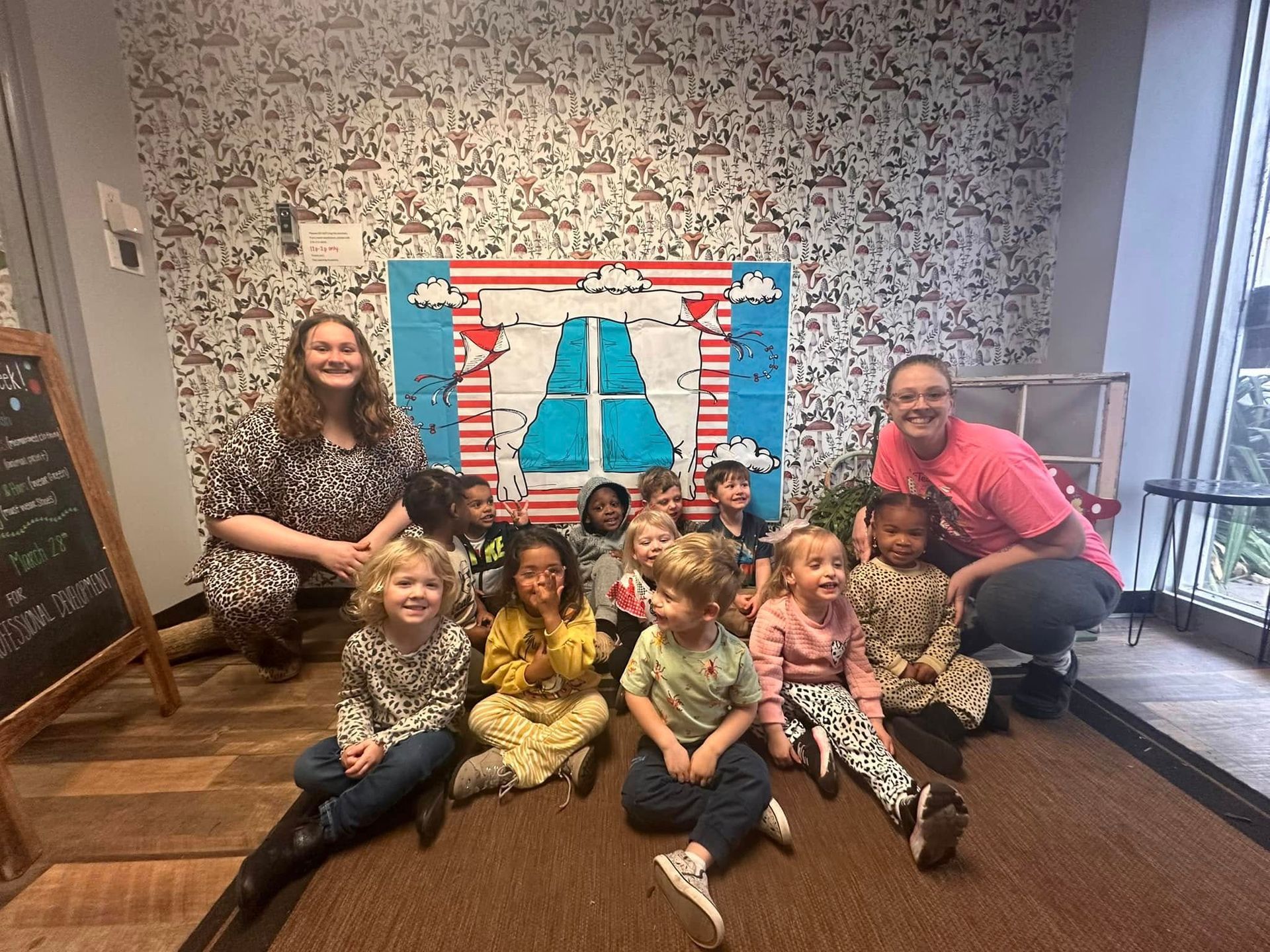 A group of children and adults are sitting on the floor in a room.
