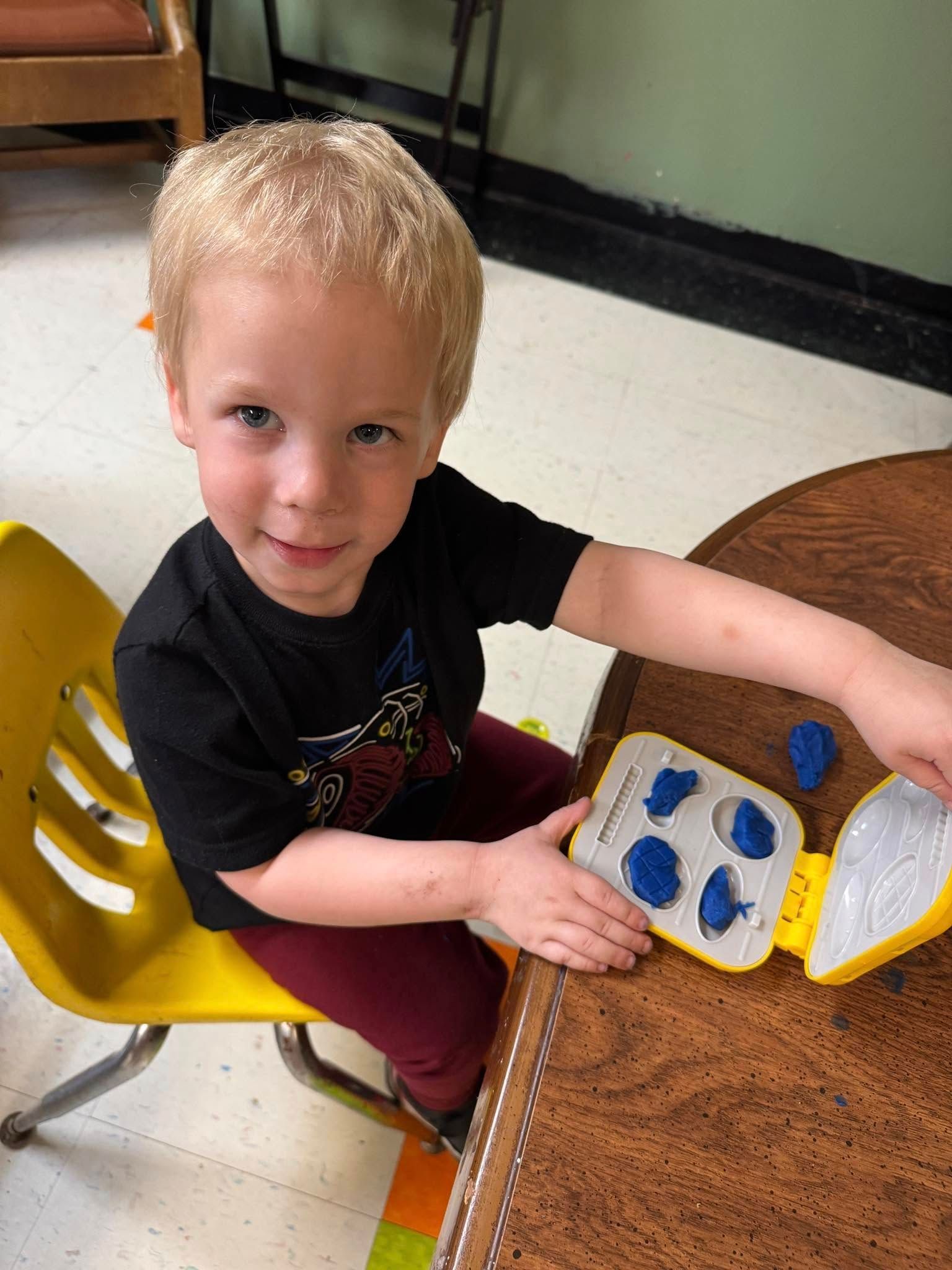 A young boy is sitting at a table playing with a toy.
