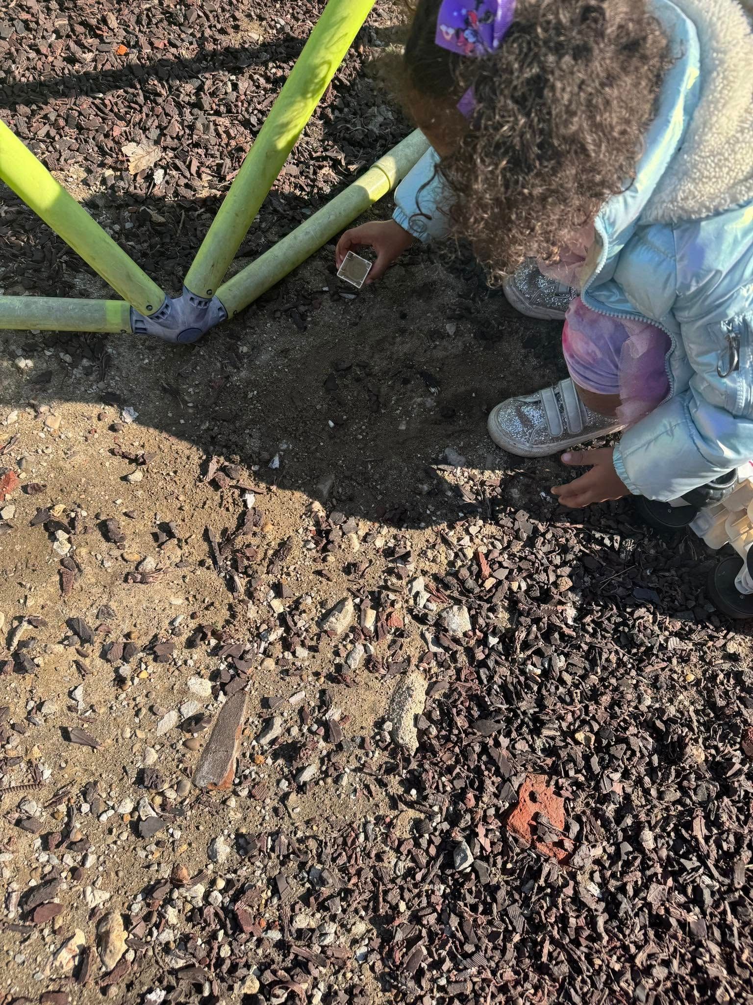 A little girl is playing in the dirt at a playground.