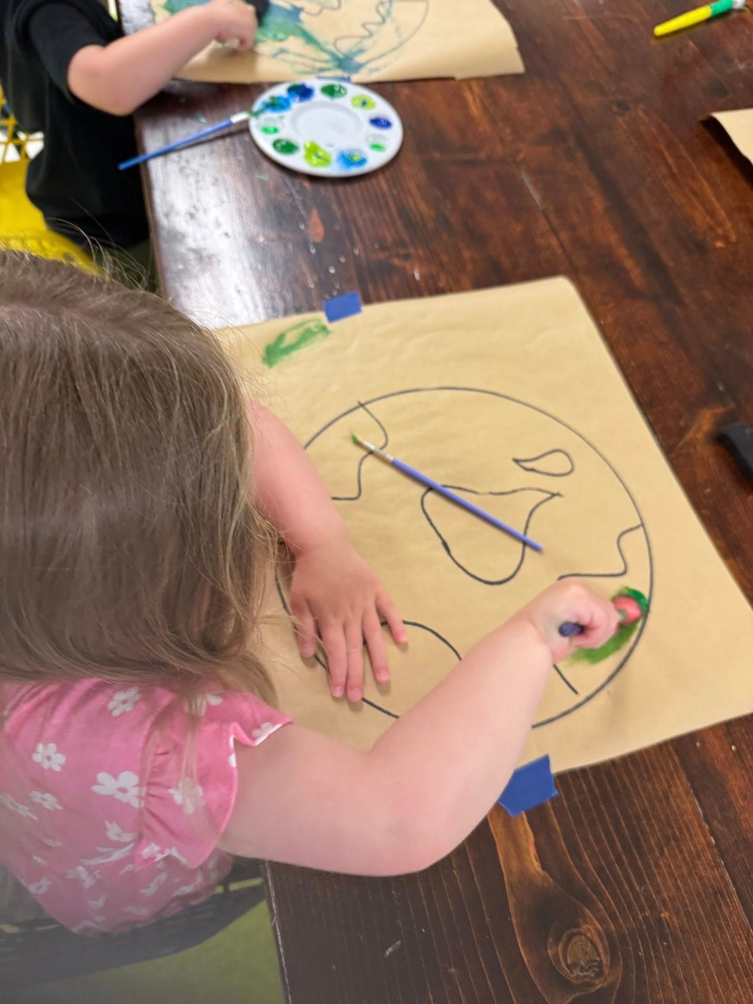 A little girl is drawing a picture of the earth on a piece of paper